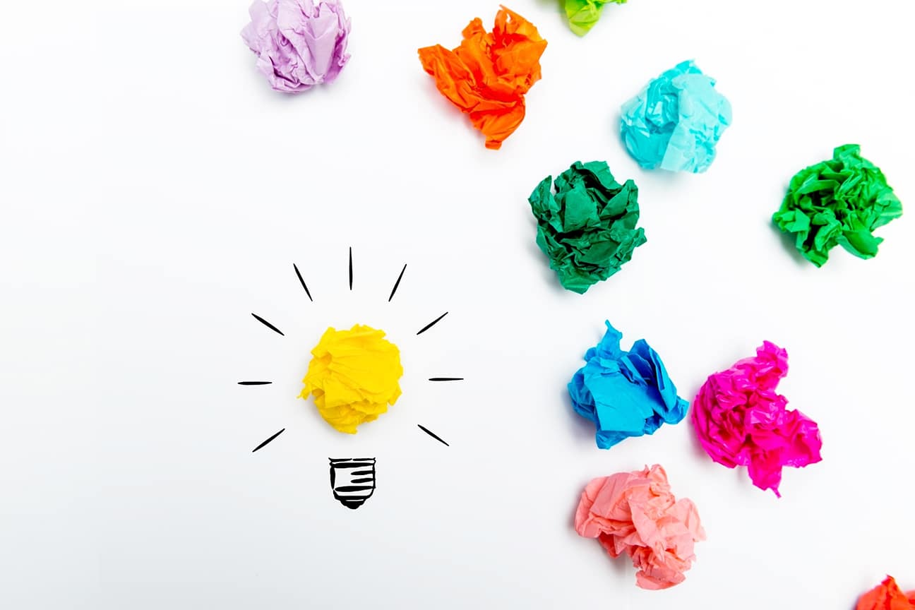 Crumpled paper light bulb over white background, surrounded by colorful Crumpled paper