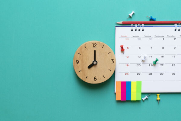 close up of calendar and clock on green background, planning for business meeting or travel planning concept